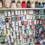 Regalwand mit zahlreichen verpackten Handyhüllen, Displayschutzfolien und Wollmützen