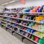 Regale in einem Geschäft, gefüllt mit bunten Knäueln Strickwolle in verschiedenen Farben.