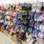 Regalwand in einem Schuhgeschäft mit vielen Hausschuhen, Sandalen und Sneakern in verschiedenen Farben.