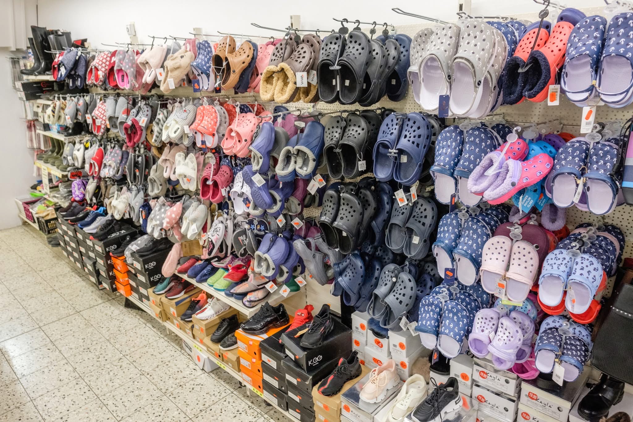 Regalwand in einem Schuhgeschäft mit vielen Hausschuhen, Sandalen und Sneakern in verschiedenen Farben.