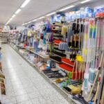 Regalwand in einem Geschäft mit verschiedenen Reinigungsbürsten, Mopps und Stielen